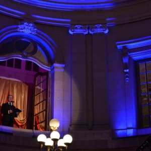 Zdjęcie przedstawia konferansjera w roli którego wystapił Pan Jacek Woleński w witrynie okiennej znajdującej się u szczytu schodów wewnątrz Pałacu Kawalera, zapowiadającego kolejne etapy koncertu pt. Percussio